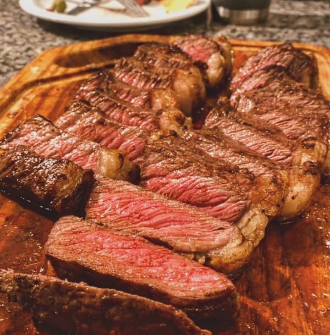 Bife ancho fatiado sobre tábua de madeira